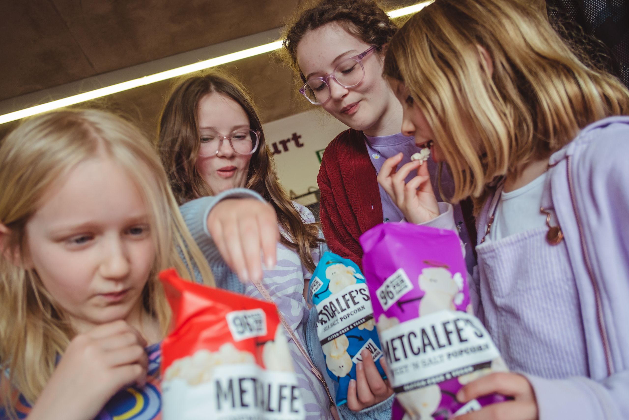 Four girls sharing bags of popcorn